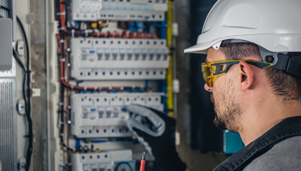 Man, an electrical technician working in a switchboard with fuses. Man, an electrical technician working in a switchboard with fuses. Installation and connection of electrical equipment.